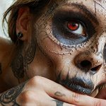 nombreux tatouages dont un de tete de mort sur la main de cette femme