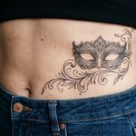 masque de venise tatoué sur un ventre féminin